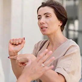 Femme en pleine conversation, utilisant la langue des signes pour communiquer. Son expression est concentrée, reflétant l'engagement dans l'échange. L'image met en avant l'importance de la communication non verbale.